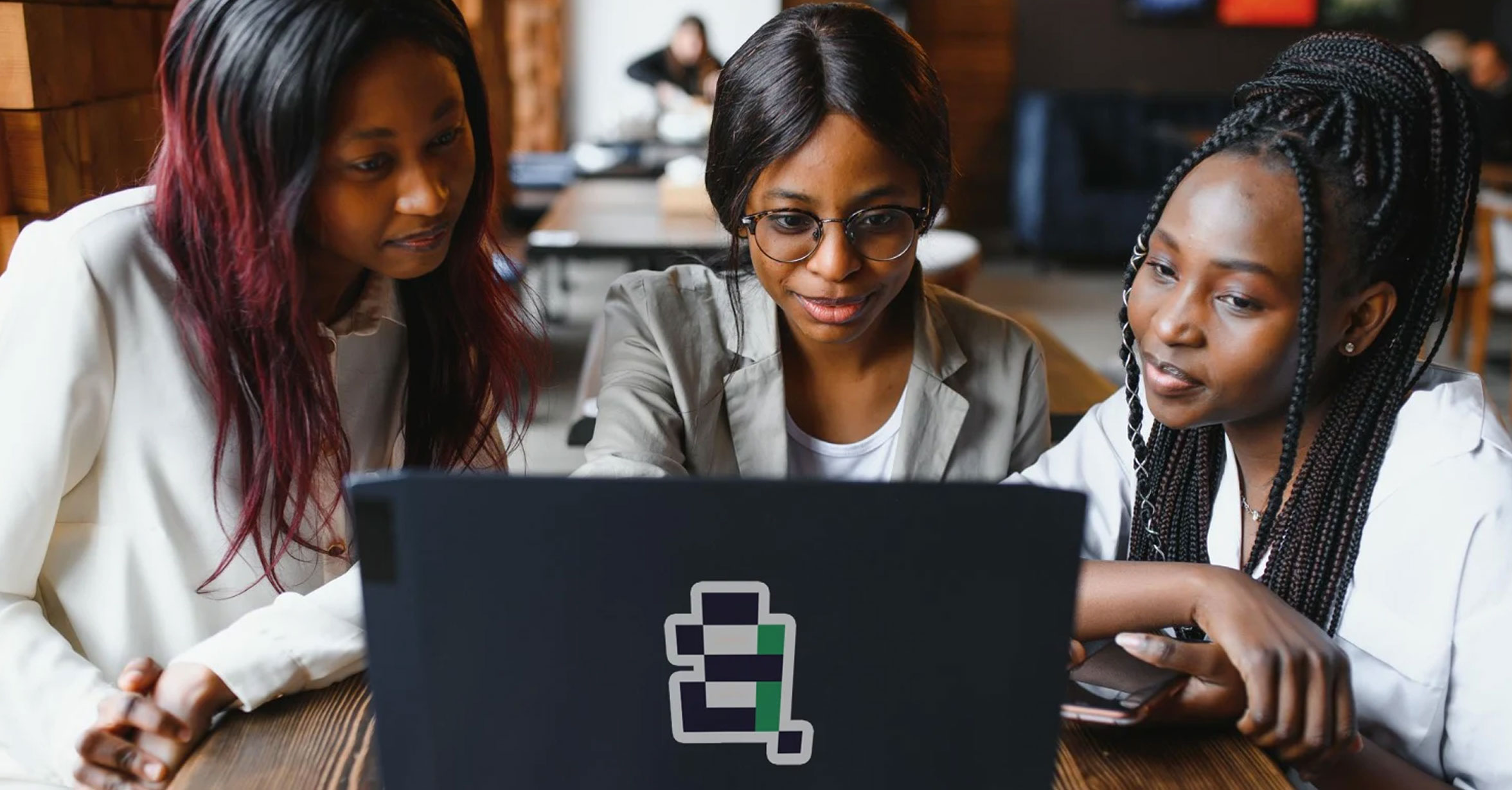 Three young women collaborating around a laptop